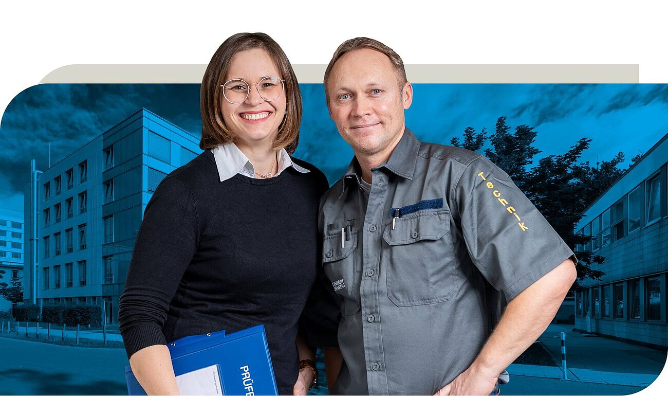 Ein Mitarbeiter in grauer Arbeitskleidung mit der Aufschrift "Technik" steht neben einer Kollegin in schwarzer Kleidung, die einen blauen Ordner hält. Beide stehen vor einem modernen Gebäude.