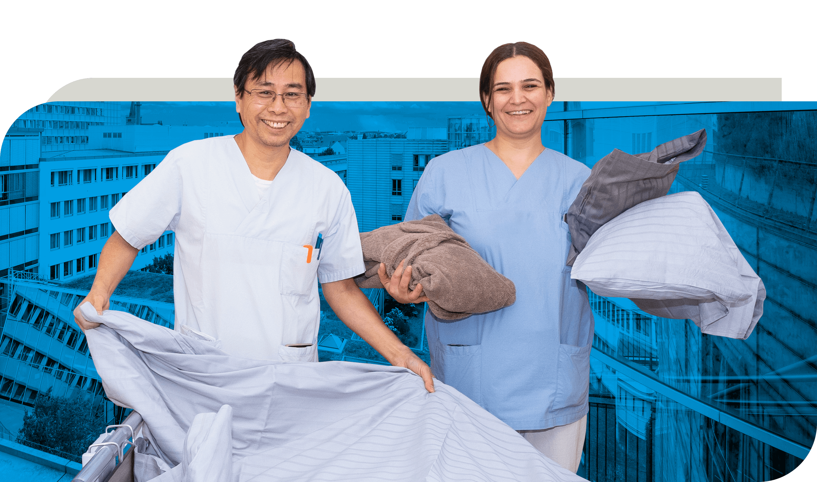 Zwei Mitarbeitende aus dem Wahlleistungs-Service in Arbeitskleidung stehen mit Bettwäsche und Handtüchern in den Händen. Eine Person hält ein Bettlaken, während die andere Handtücher und Kissenbezüge trägt. Im Hintergrund ist ein modernes Gebäude zu sehen