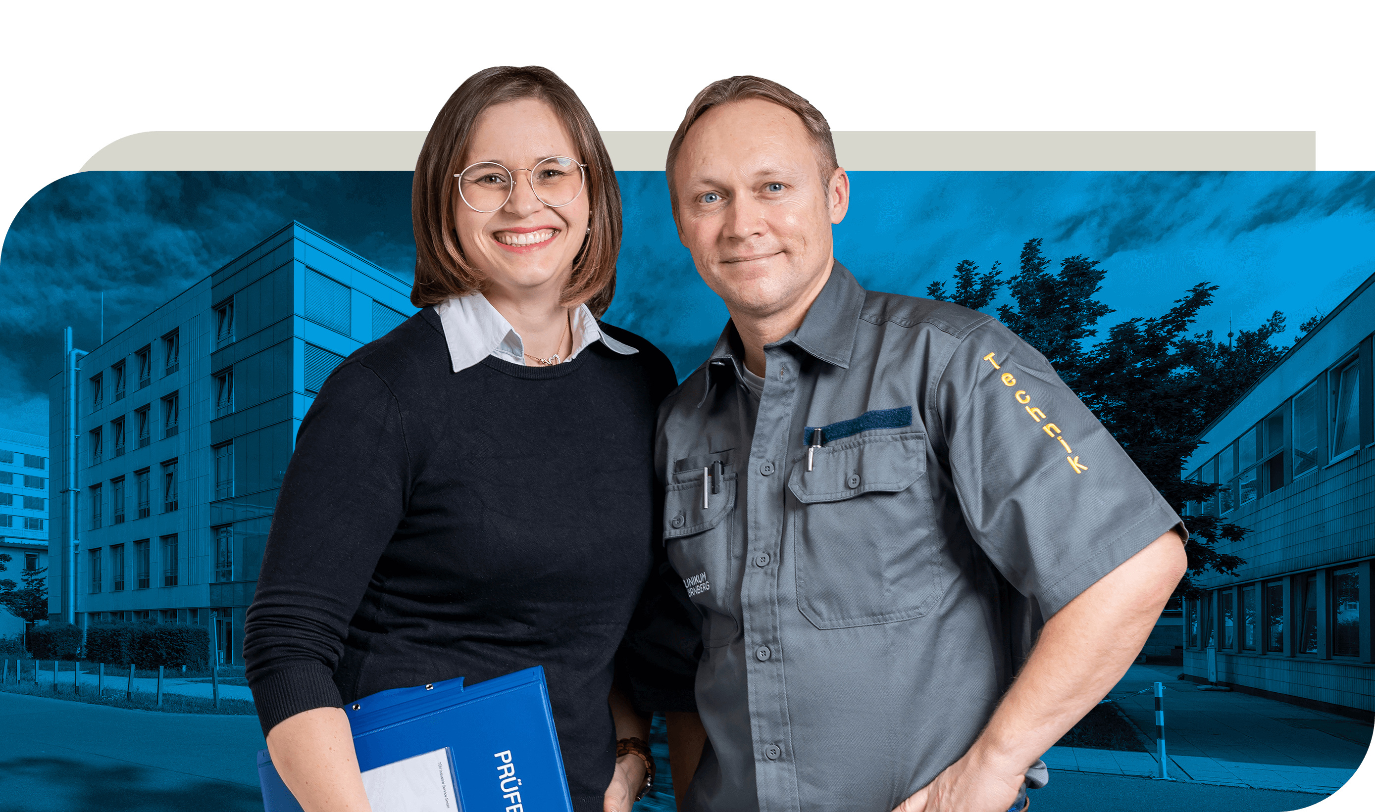 Ein Mitarbeiter in grauer Arbeitskleidung mit der Aufschrift "Technik" steht neben einer Kollegin in schwarzer Kleidung, die einen blauen Ordner hält. Beide stehen vor einem modernen Gebäude.