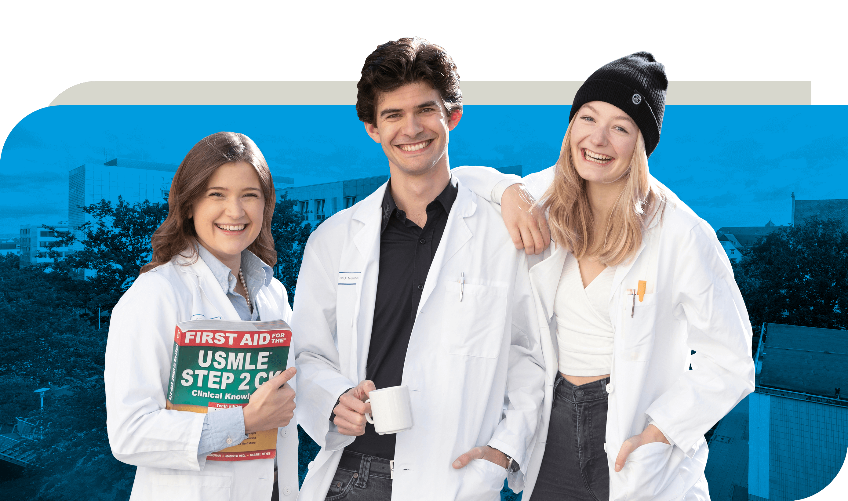 Drei Medizinstudierende in weißen Kitteln stehen lachend zusammen. Eine Frau hält ein Lehrbuch mit der Aufschrift ‚First Aid for the USMLE Step 2 CK‘, ein Mann hat eine Tasse in der Hand, und eine andere Frau trägt eine schwarze Mütze und lächelt herzlich