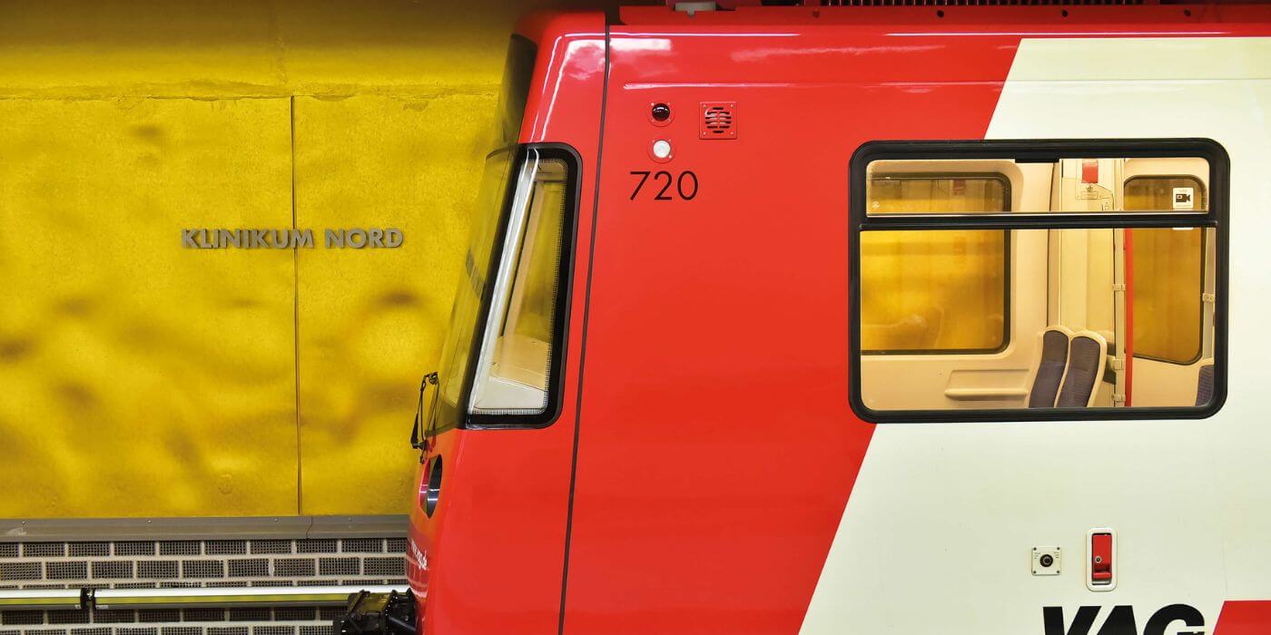 Eine rote U-Bahn vor einer gelben Wand mit der Aufschrift 'Klinikum Nord'. Das Bild symbolisiert eine gute Verkehrsanbindung für Mitarbeiter