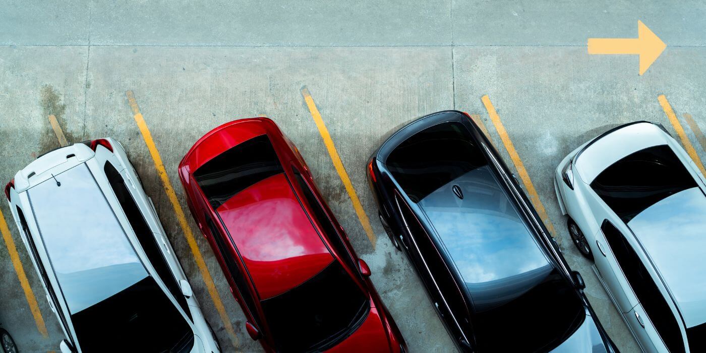 Ein Parkplatz mit markierten Stellplätzen auf einem asphaltierten Untergrund. Das Bild steht für Mitarbeiterparkplätze