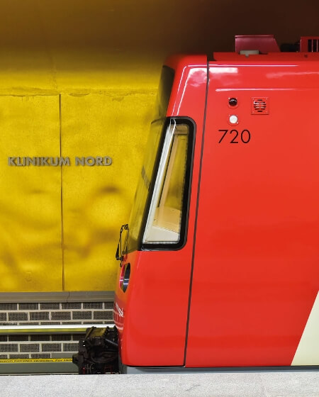 Eine rote U-Bahn vor einer gelben Wand mit der Aufschrift 'Klinikum Nord'. Das Bild symbolisiert eine gute Verkehrsanbindung für Mitarbeiter