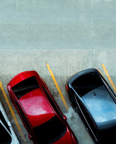 Ein Parkplatz mit markierten Stellplätzen auf einem asphaltierten Untergrund. Das Bild steht für Mitarbeiterparkplätze