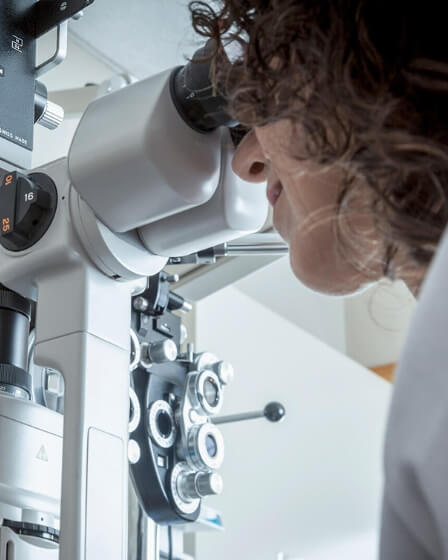 Eine Person führt eine augenärztliche Untersuchung durch und blickt durch ein modernes ophthalmologisches Gerät