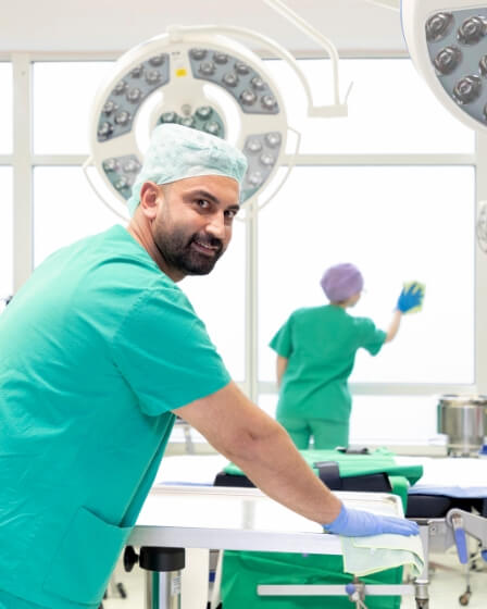 Eine Reinigungskraft in OP-Kleidung desinfiziert sorgfältig eine Arbeitsfläche in einem Operationssaal