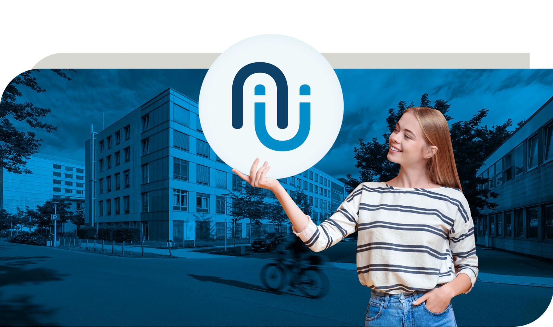 Eine junge Frau steht vor einem modernen Gebäude und hält ein rundes Schild mit dem Logo des Klinikums Nürnberg in einem stilisierten Design. Im Hintergrund sind weitere Gebäude und ein Fahrradfahrer zu sehen. Das Bild ist in Blautönen gestaltet, wodurch es einen modernen und dynamischen Eindruck vermittelt.
