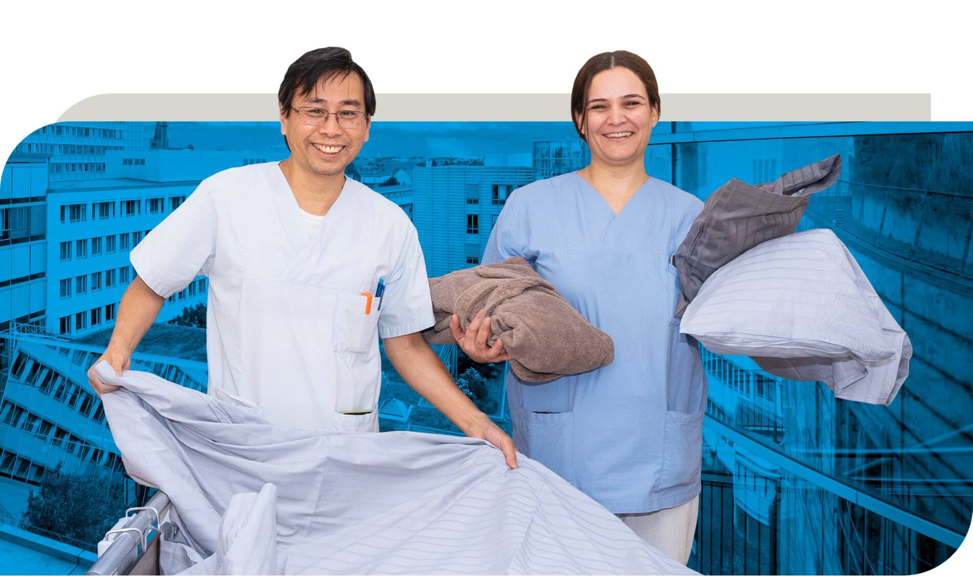 Zwei Mitarbeitende aus dem Wahlleistungs-Service in Arbeitskleidung stehen mit Bettwäsche und Handtüchern in den Händen. Eine Person hält ein Bettlaken, während die andere Handtücher und Kissenbezüge trägt. Im Hintergrund ist ein modernes Gebäude zu sehen